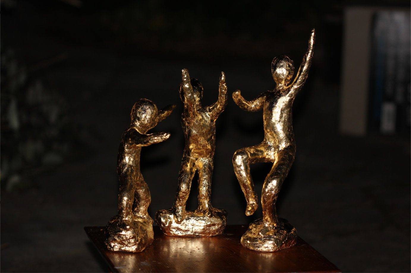Group of three sculptures of abstract people dancing gold leafed
